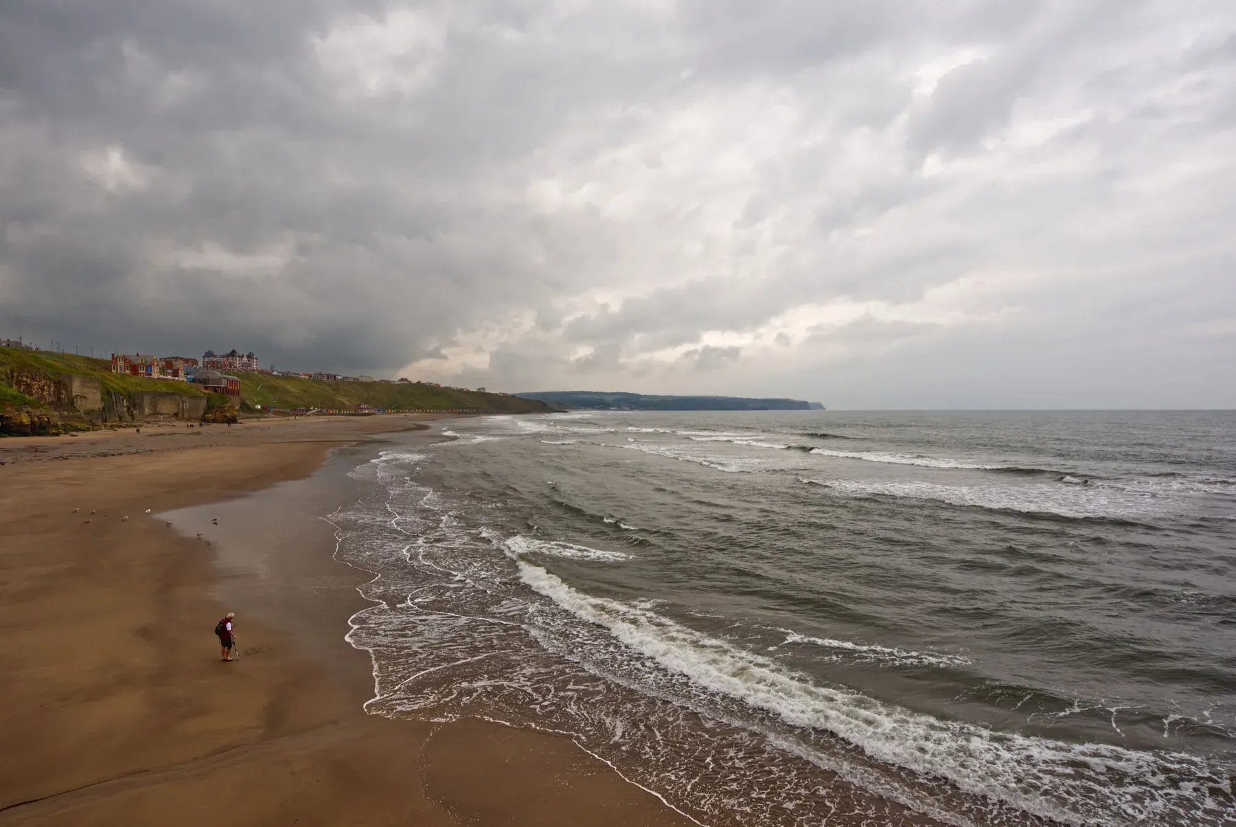 The long sands below Whitby's West Cliff, with the beach huts and the town on the cliff top beyond